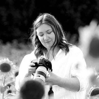 Fotograf Emma Elise med kamera i en solsikkemark – emmaelisefoto på Instagram