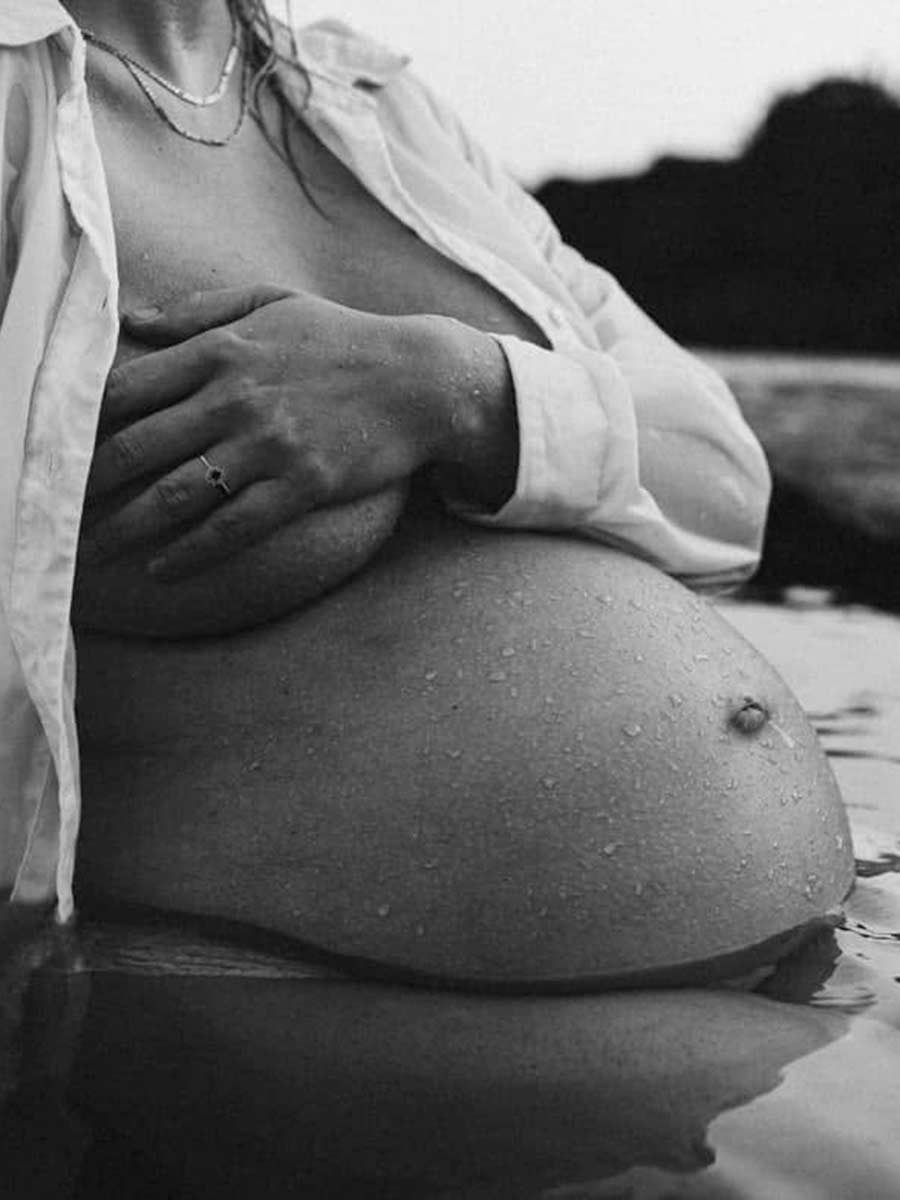 Tidløs og æstetisk graviditetsfotografering i smukke sort-hvide nuancer. Nærportræt af fin rund babybule ved vandet i Jylland og Østjylland.
