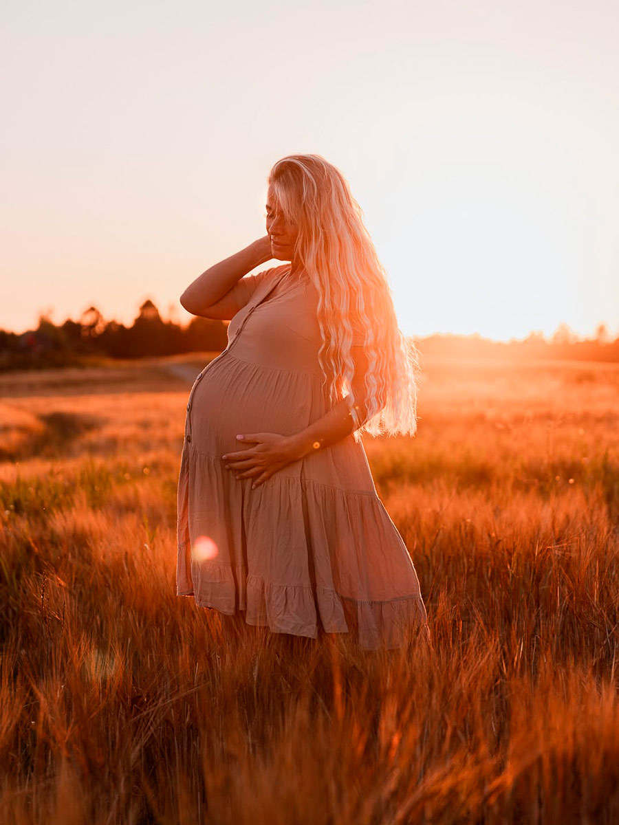 Varm og naturlig graviditetsfotografering i den gyldne time på en åben mark nær Randers. Professionelle og nærværende graviditetsbilleder i Østjylland.